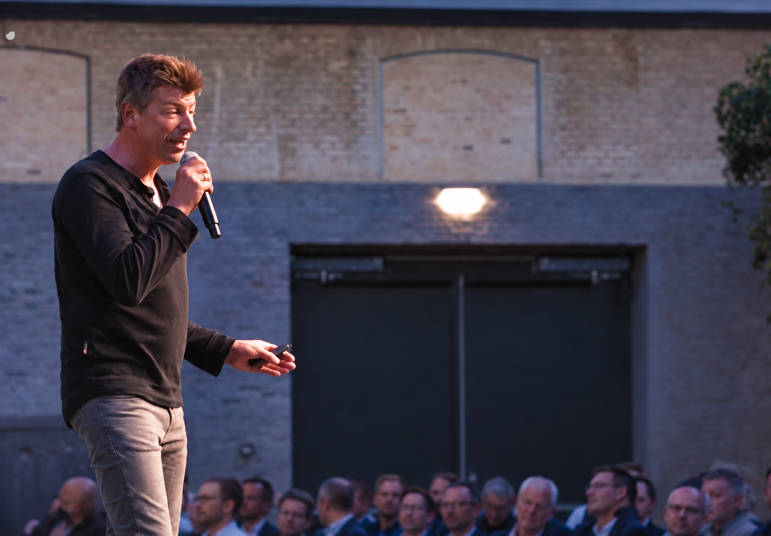 Rasmus Skovmand speaking into a microphone in front of an audience.